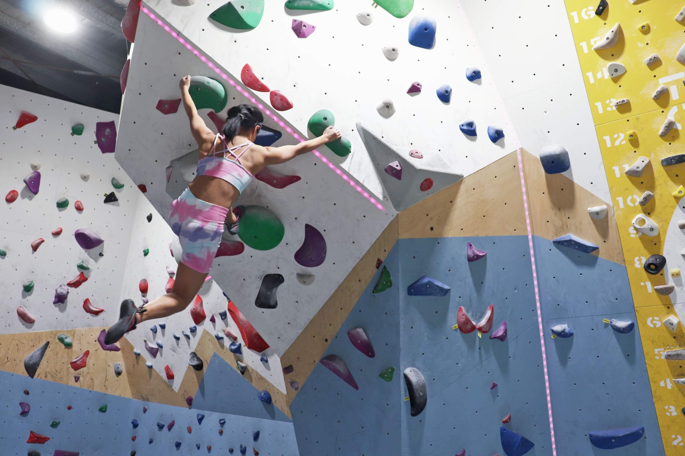 Woman climbing on colorful bouldering wall